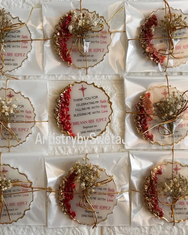 These are the beautifully packaged baptism return favors I created for a client. Each personalized plaque is tied with a delicate ribbon and a sprig of dried flowers, ready to be gifted.