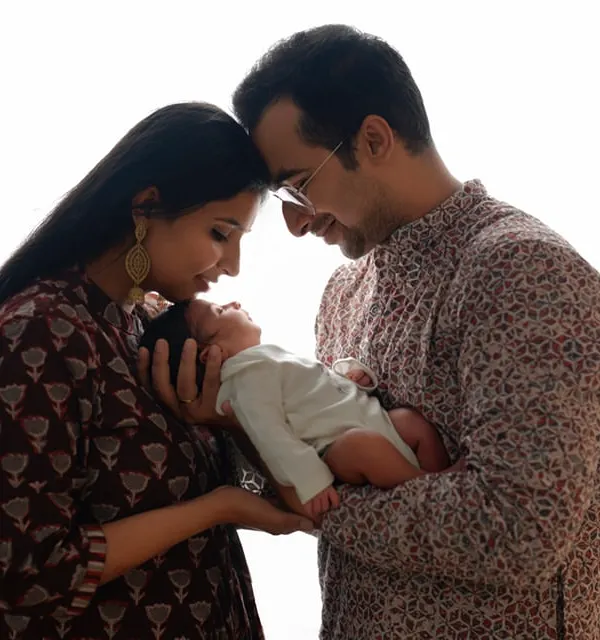 A silhouette-style portrait of new parents admiring their baby. This image beautifully captures the intimate, quiet moment of a new family forming.