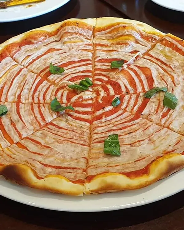 A visually striking pizza with a spiral of tomato sauce and my homemade vegan cheese. This shows that food can be playful and artistic while still being completely healthy and plant-based.