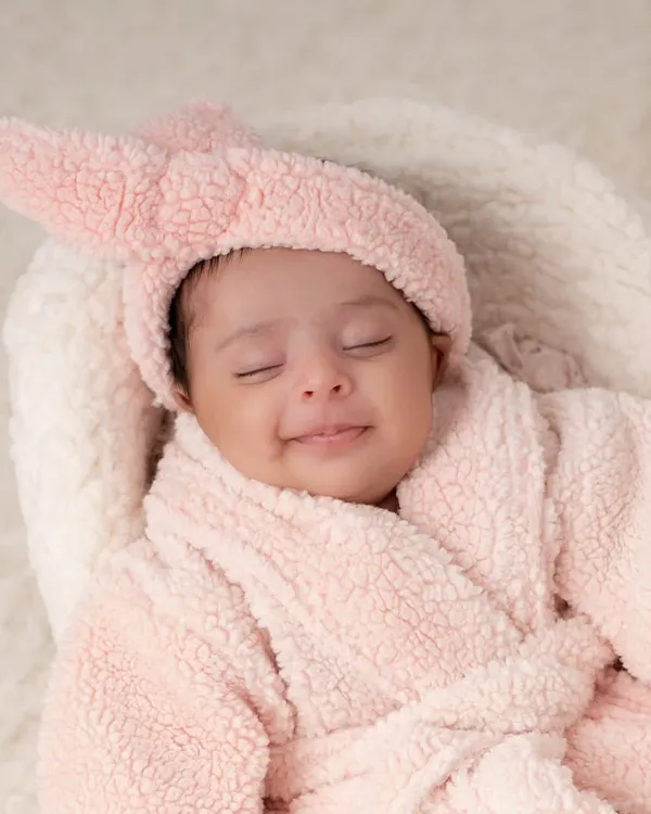 A close up of a one month old baby enjoying her "spa day". The soft pink robe and contented smile make for an adorable and unique milestone photo.
