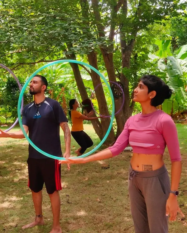 A candid shot of participants learning hoop isolations together outdoors, capturing the hands-on, communal learning experience at a flow fest.