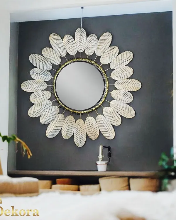 This large decorative mirror is framed with white metal leaves that have a subtle texture. It's a stunning centerpiece for a bedroom or entryway, shown here against a dark wall for maximum impact.