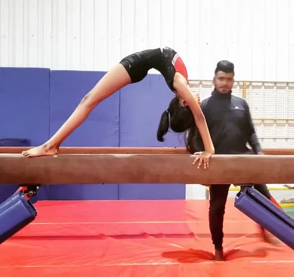 I'm spotting a student as she practices a back walkover on the low beam. This builds her confidence before moving to the high beam.