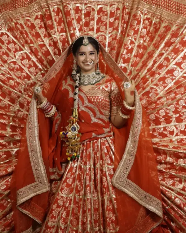 This classic red bridal lehenga with intricate gold work and a dramatic fanned-out skirt is a perfect example of the timeless wedding look I can create for you.