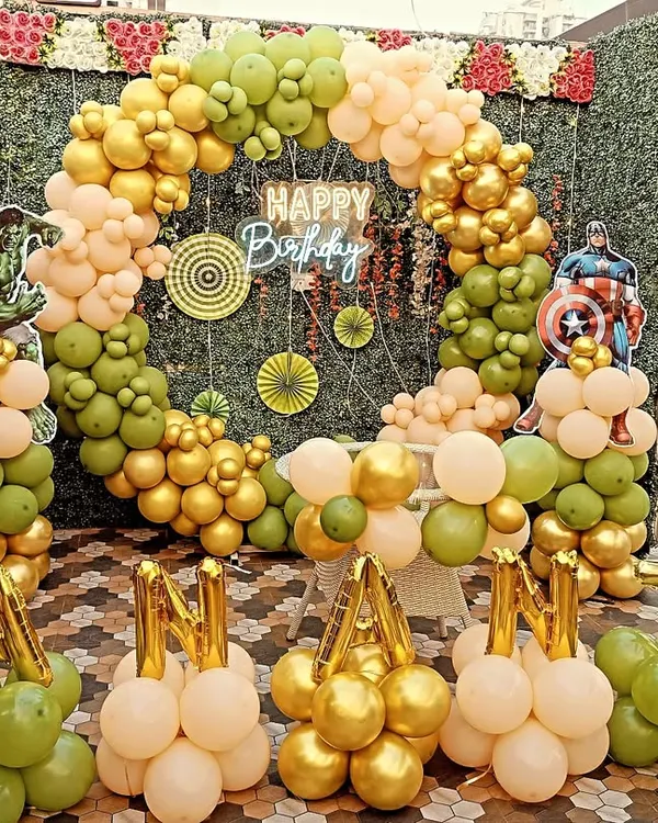 An Avengers-themed birthday party with a full balloon ring against a green wall. This setup includes Hulk and Captain America cutouts and balloon letters spelling out the birthday boy's name.
