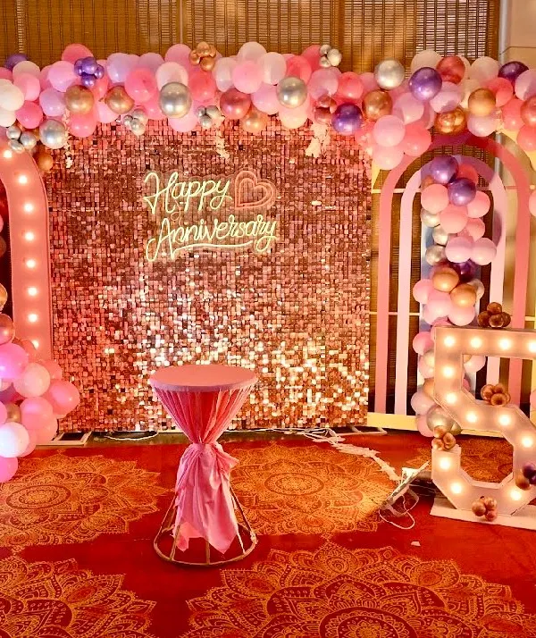 A grand setup for a 50th anniversary party. We used a rose gold sequin wall, illuminated marquee numbers, and elaborate balloon arches in pink and pastel tones to create a festive and elegant photo zone.