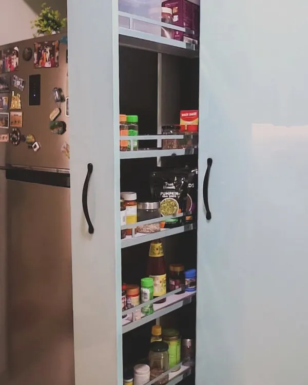 This tall pull-out pantry unit is a perfect example of our smart storage solutions. It utilizes vertical space next to the refrigerator, providing multiple shelves for organizing spices, jars, and packaged goods.
