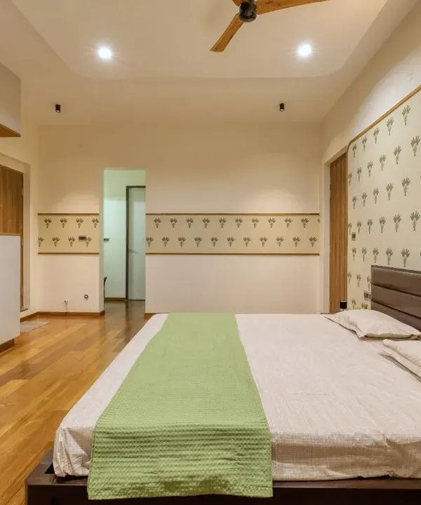 The parents' bedroom at Villa 17, designed for warmth and comfort. The space features a tropical-inspired wallpaper and custom wardrobes with sage green arched panels.