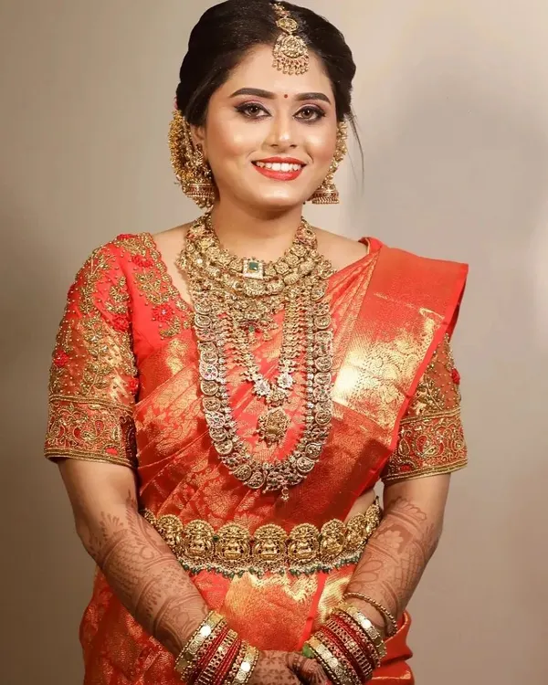 This is the result of a collaborative journey to create a classic, timeless South Indian bridal look. We focused on selecting a radiant red Kanjivaram saree that perfectly complemented her skin tone and paired it with intricate temple jewelry to achieve this stunning outcome.