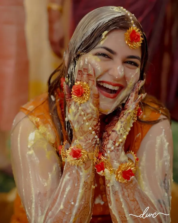 The pure, unadulterated joy of a Haldi ceremony. The bride's ecstatic expression, covered in turmeric and flowers, is absolutely priceless.