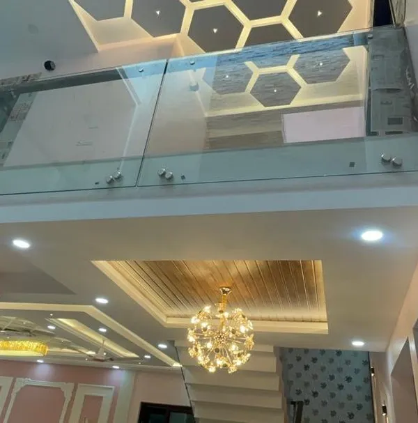 A view of a double-height ceiling space featuring a glass bridge and a hexagonal-patterned false ceiling on the upper level. This design adds architectural interest and a sense of luxury.