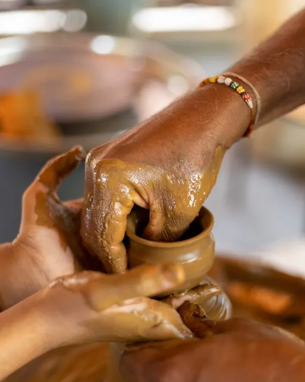 An instructor guides a guest's hands in pottery, a beautiful moment of shared creativity and learning.