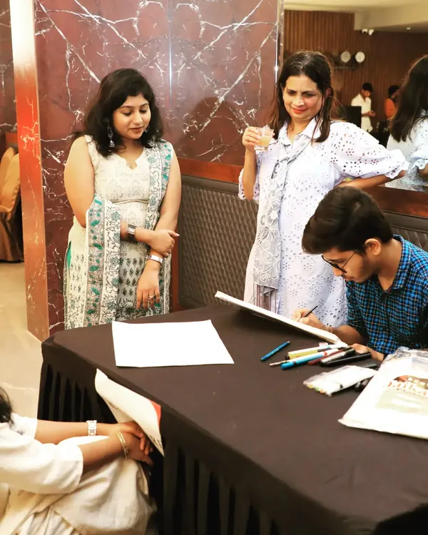 Guests watch as a caricature artist creates a fun, personalized souvenir at a corporate event for Fern Hotels & Resorts. These interactive stations are an excellent way to encourage mingling and provide guests with a unique takeaway.