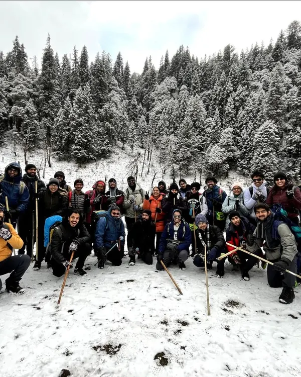 Our trekking group posing in the snow covered forests on the way to the Kedarkantha summit. The camaraderie and shared challenge make the cold totally worth it.