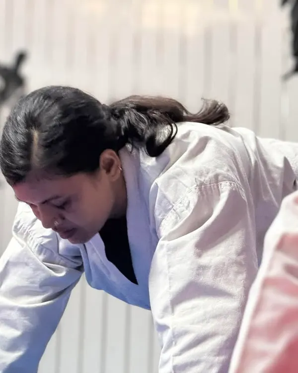 The determination and focus required in martial arts are clearly visible on this student's face as she pushes through a difficult training exercise.