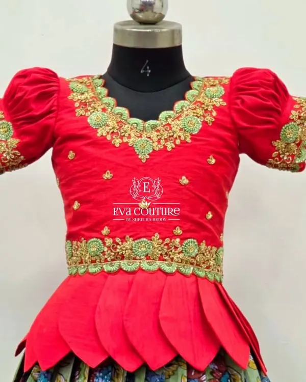 A close-up of a red blouse with stunning green and gold maggam work. This intricate hand embroidery is what makes each piece unique.