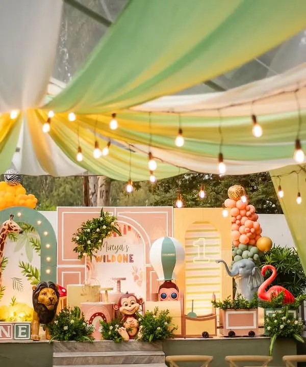 A stunning wide shot of Mireya's boho 'Wild One' party. The setup features a beautiful tent-style draping, a custom-designed backdrop with pastel colors, and a whole crew of friendly jungle animals.