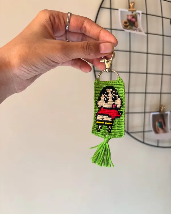 Here's a custom keychain I made featuring Shinchan. The design is created by knotting individual threads to form the pixel-like image, complete with his signature red shirt.