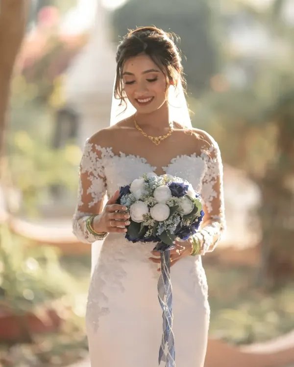 A radiant bride, lost in a happy thought just before the ceremony. The soft, natural light highlights her beautiful smile and the delicate details of her wedding gown.