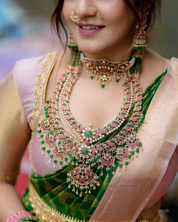 A detailed close-up of a magnificent layered Polki and Kundan bridal set. The combination of pink and green stones with uncut diamonds and pearls creates a breathtakingly grand look.