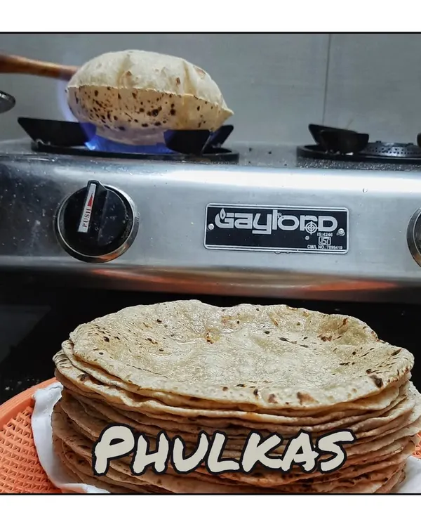 The heart of my kitchen: making soft, fluffy Phulkas. Each one is cooked on the tawa and then puffed up on an open flame, ensuring they reach you fresh and warm.