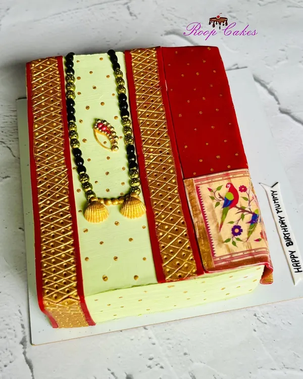 A slice of tradition. This stunning cake is designed to look like a folded Paithani saree, complete with an edible mangalsutra and nath. It's a beautiful tribute to our culture, made entirely from whipped cream and fondant.
