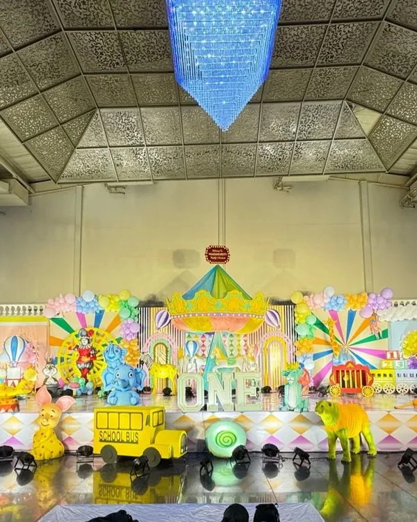 A massive, colorful carnival stage featuring a carousel centerpiece, circus train props, and vibrant backdrops.