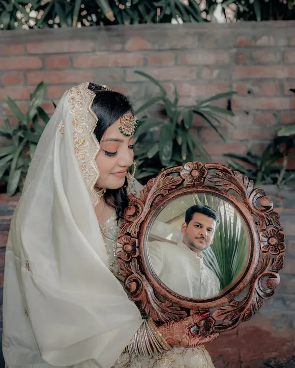 A creative and symbolic portrait where the bride, Lubna, holds a mirror reflecting her groom, Wamiq. This shot beautifully represents seeing one's world in their partner.