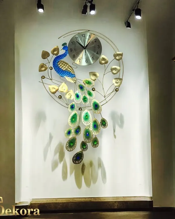 A full view of our metal peacock clock, showcasing the vibrant blue and green details of its cascading tail. It's a handmade statement piece for any large wall.