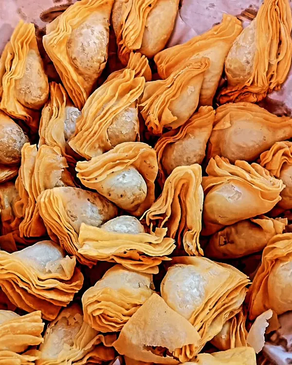 A fresh batch of our handmade Warkhi Samosas. The intricate, flaky pastry is a hallmark of this traditional snack, available with mutton, chicken, or vegetable fillings.