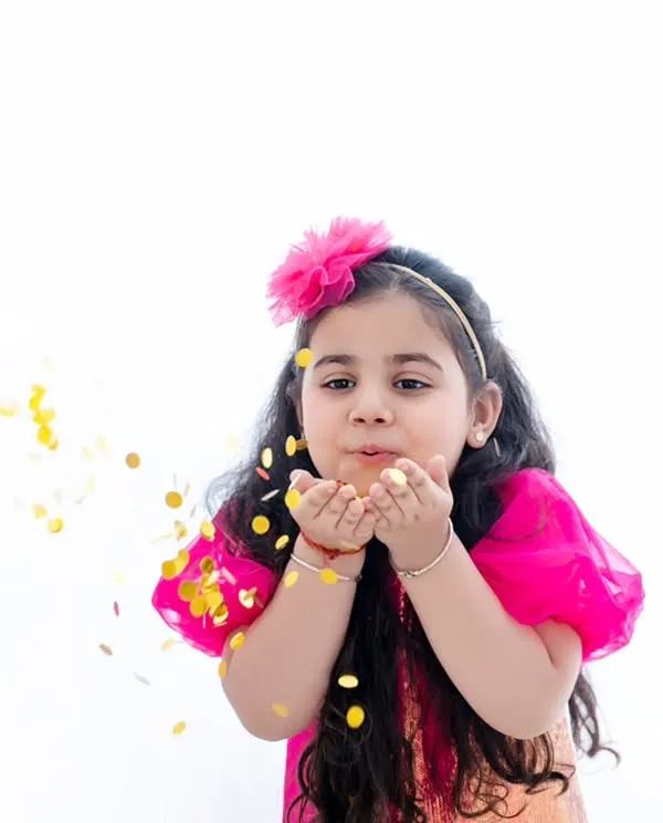 Making a wish. This action shot of a young girl blowing glitter towards the camera is full of magic and movement.