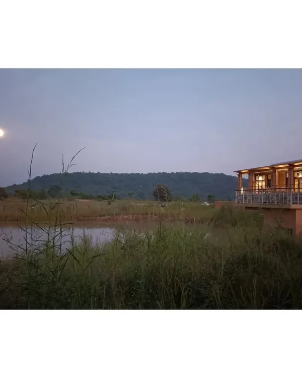 The Waghoba Ecolodge at dusk, overlooking a man-made lake designed to restore the area's biodiversity. The resort, built with adobe blocks from site soil, offers a tranquil experience of living in harmony with the forest near Tadoba Wildlife Sanctuary.