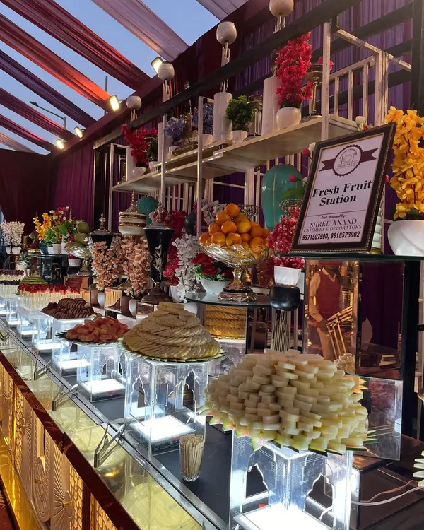 A beautifully arranged fresh fruit station is a healthy and colorful addition to any event. This display features a variety of seasonal fruits, from whole oranges to sliced kiwis and dates on skewers, all presented artfully.