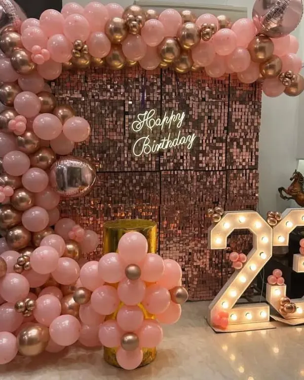 A glamorous 23rd birthday setup featuring a stunning rose gold sequin wall, a custom neon sign, and a beautiful organic balloon arch in shades of pink and chrome. This is perfect for milestone birthdays like the 18th, 21st, or 30th.