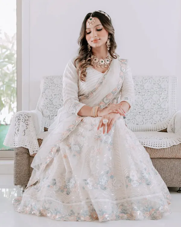A vision in white. This bride looks absolutely angelic in an ivory lehenga, paired with a stunning Kundan and pearl necklace set. This is a perfect look for a serene daytime ceremony.