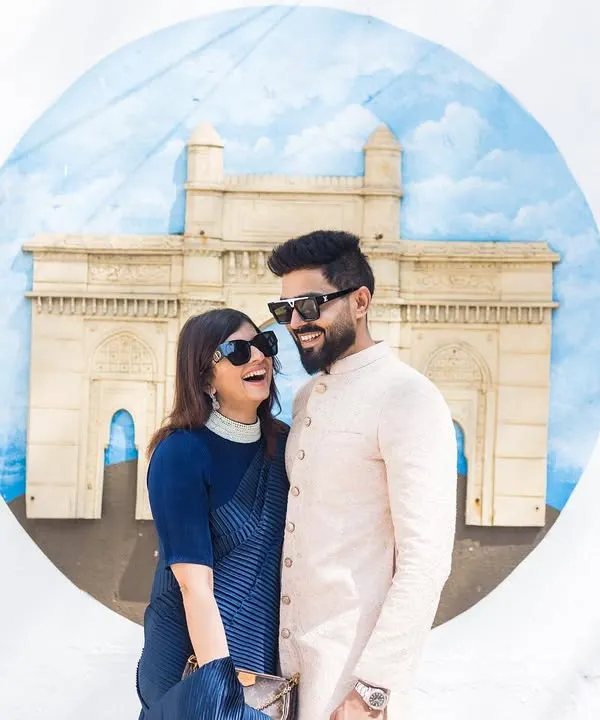 A candid, laughing moment in front of a Gateway of India mural. This shot captures the fun, urban vibe of a Mumbai pre-wedding shoot.