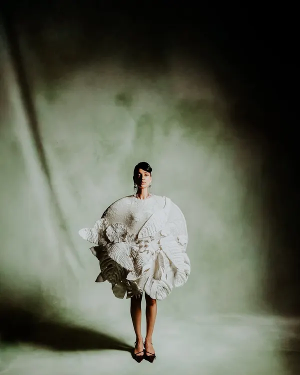 A full-length shot for designer Rahul Mishra, focusing on the garment's sculptural form and movement. The dramatic lighting and minimalist backdrop create a high-fashion, avant-garde mood.