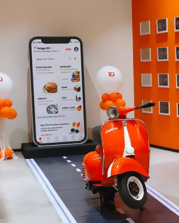 **(Hero Media)** We designed this interactive photo booth for the Swiggy Annual Awards, featuring a giant smartphone display and their iconic orange scooter. It's a great example of how we integrate a company's brand identity into a fun and memorable experience for their employees.