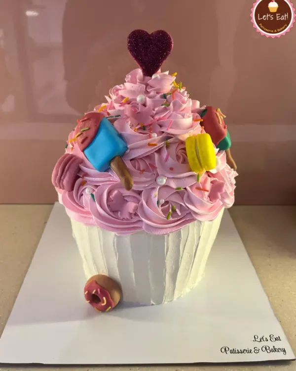 Why have a cupcake when you can have a giant cupcake cake? This fun design is frosted with pink buttercream and decorated with tiny edible macarons and popsicles for a super sweet celebration.