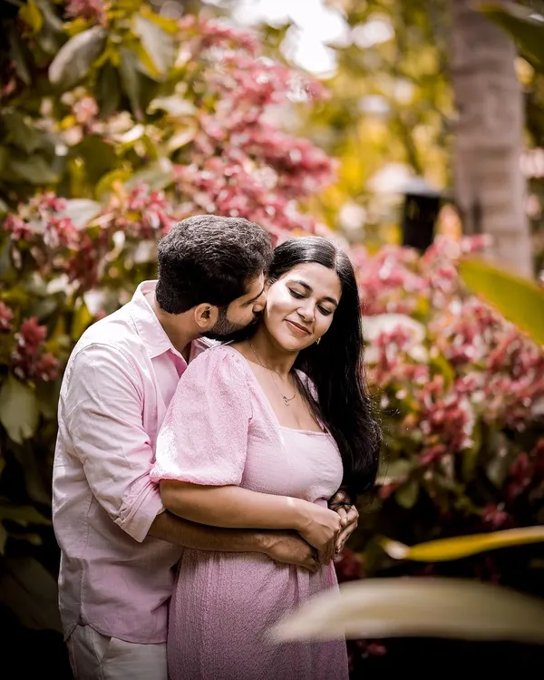 A romantic kiss in the garden, surrounded by beautiful pink flowers. A perfect, intimate moment for a pre-wedding shoot.