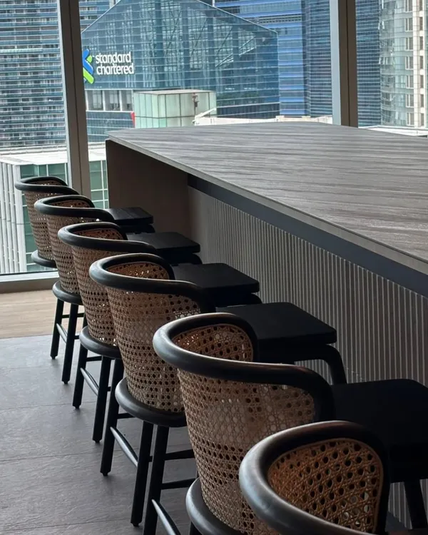 A row of my custom-made bar stools with cane backs and black frames, installed at a corporate office bar in a high-rise with a city view.