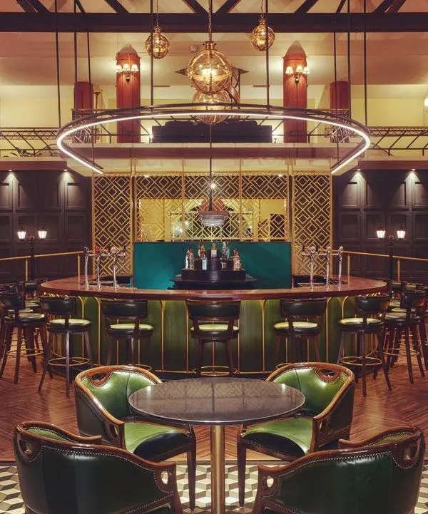 A head-on view of the Double Eagle Bar at KGA, where the lighting design balances drama and comfort. The circular fixture provides functional light over the bar while accent lights define the seating areas, creating an inviting space for patrons.