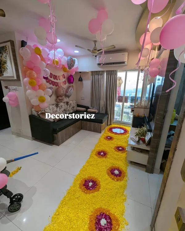 A grand welcome for a baby girl, featuring a long, beautiful flower petal runner leading into a room filled with pink and white balloons. This setup creates a stunning first impression.
