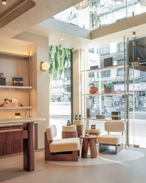 We designed the Entisi Chocolatier flagship store in Pune to be a minimal and clean canvas, allowing the vibrant products to take center stage. This view showcases the double-height space, custom lounge furniture, and sleek shelving, all working together to create an atmosphere of quiet luxury and guide the customer's journey.