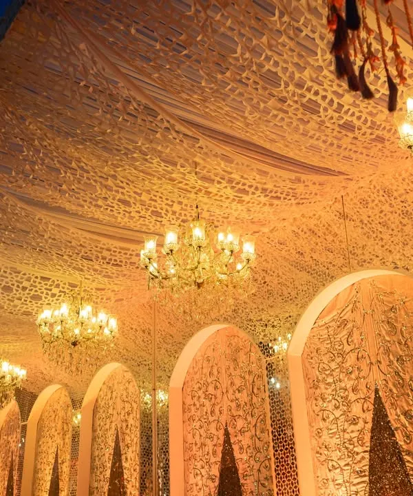 An opulent wedding setup with intricate ceiling drapery and sparkling crystal chandeliers. This image showcases our ability to cater to grand, luxurious events where every detail exudes elegance.