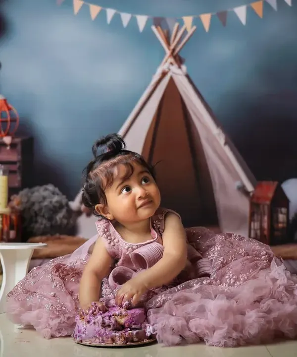 A princess enjoying her first birthday cake in our whimsical teepee setup. We love combining themes to create a truly unique cake smash photoshoot.