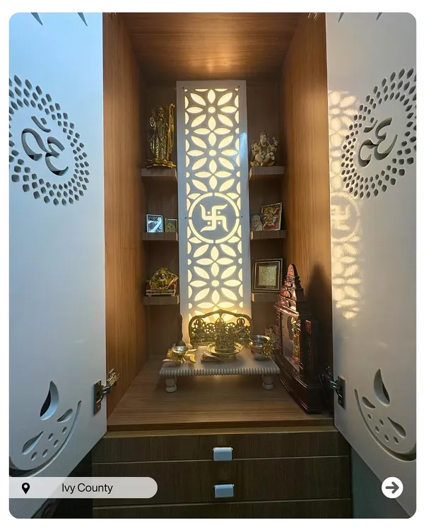 A beautiful pooja unit with backlit jaali doors featuring the 'Om' symbol. The interior has ample shelving for idols and drawers for storage, creating a serene and organized sacred space.