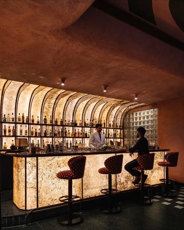 The bar at Idylll restaurant is designed as a glowing monolith. The backlit, textured facade creates a warm and inviting focal point, drawing guests into the heart of the space.