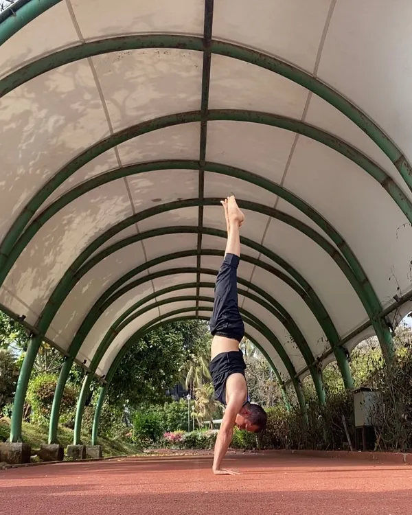 A quiet moment holding a handstand. The clean lines of this walkway create a frame for the pose, emphasizing the stillness and control required for Adho Mukha Vrksasana.