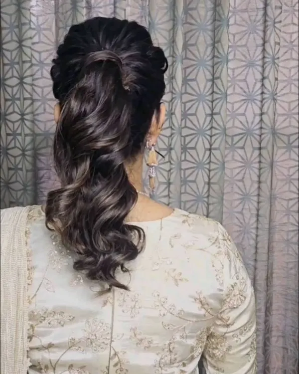 A chic and voluminous ponytail hairstyle. This is a great option for a modern yet elegant look, perfect for a reception or cocktail party.